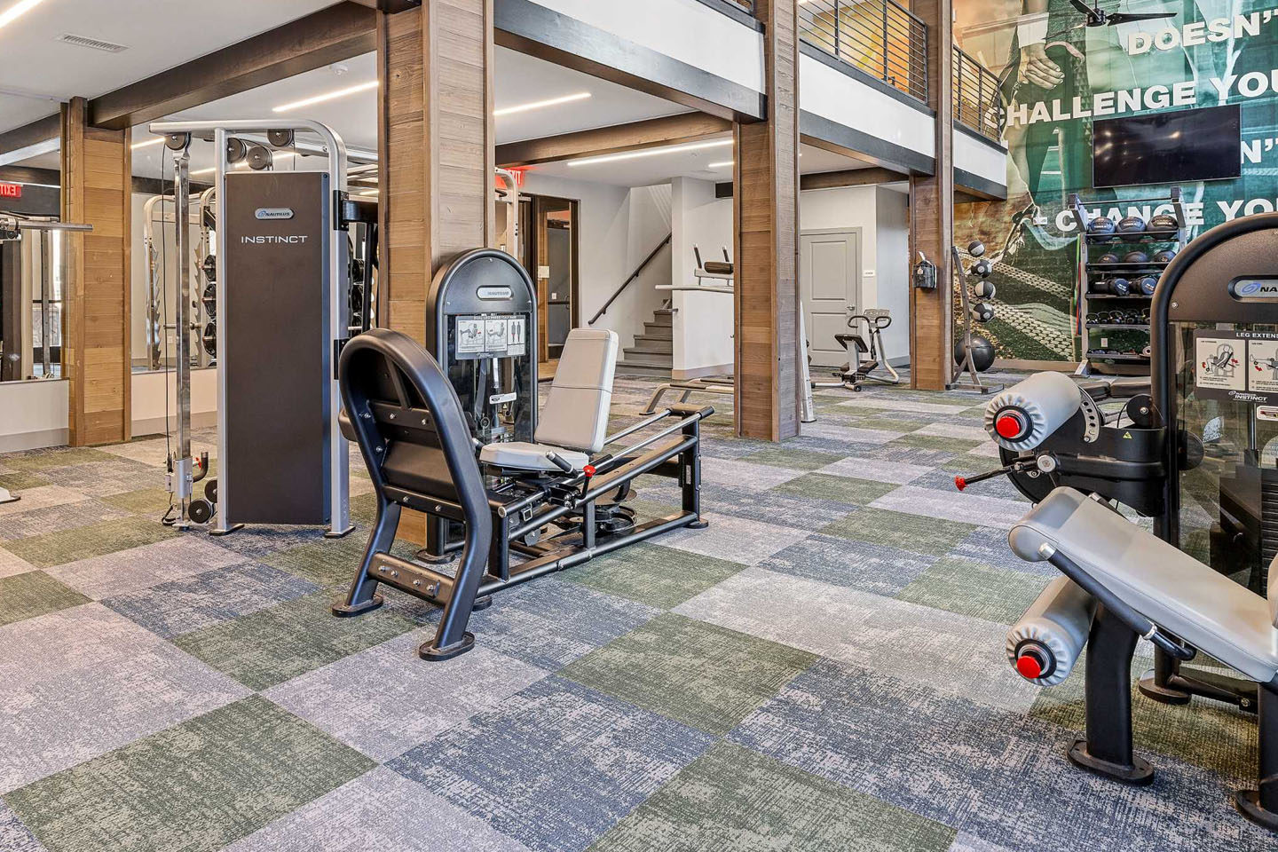 Fitness center with various types of equipment, weight training tools, TV, and an upstairs area overlooking it.