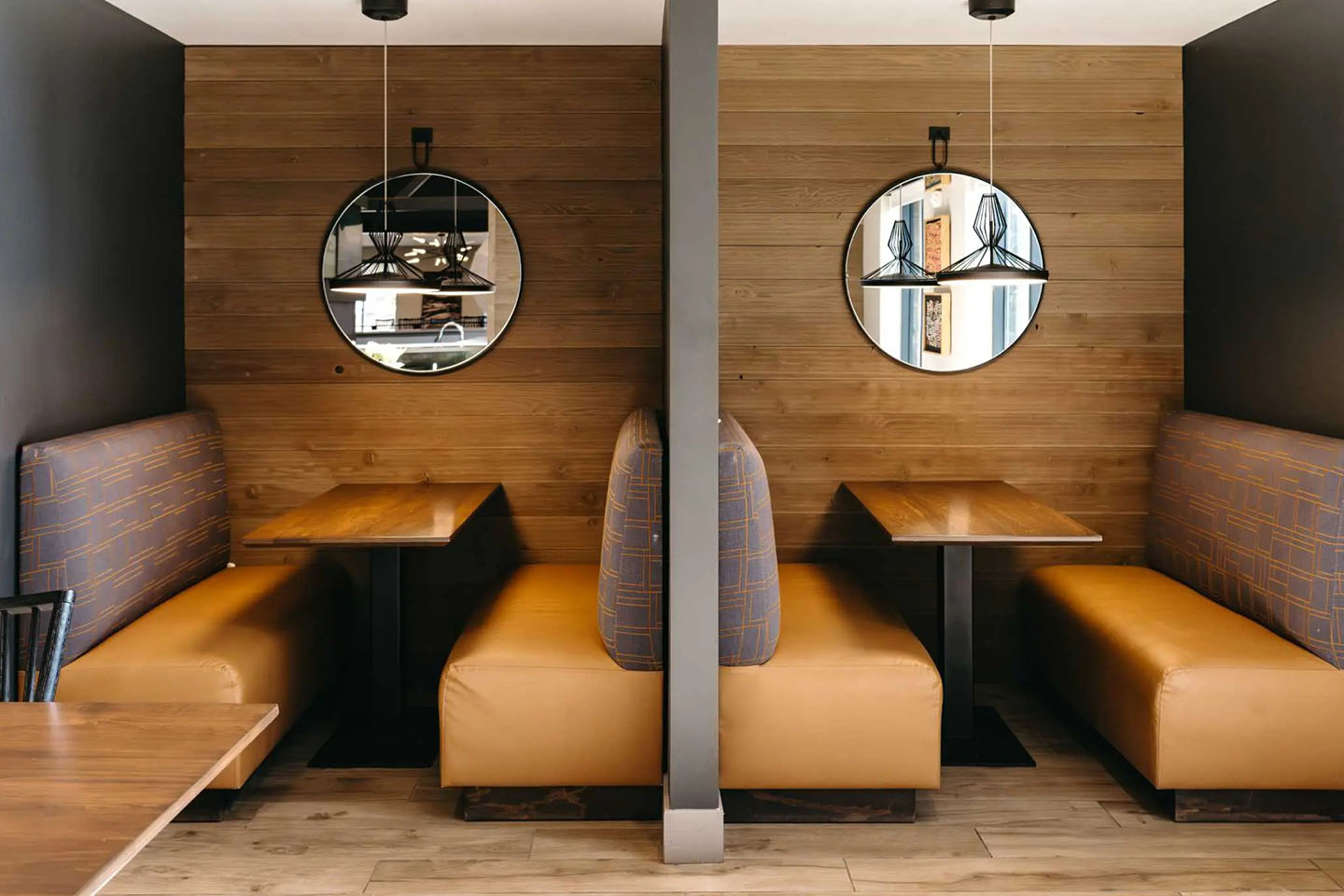 Two back-to-back study tables with booth-style seating are divided by a wall.